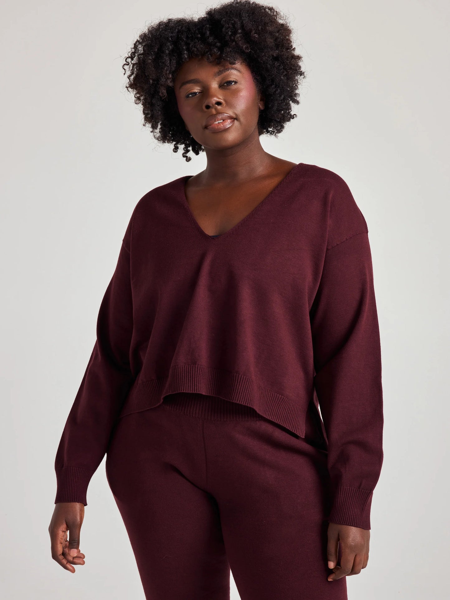model wears sustainable cozy v neck sweater in burgundy