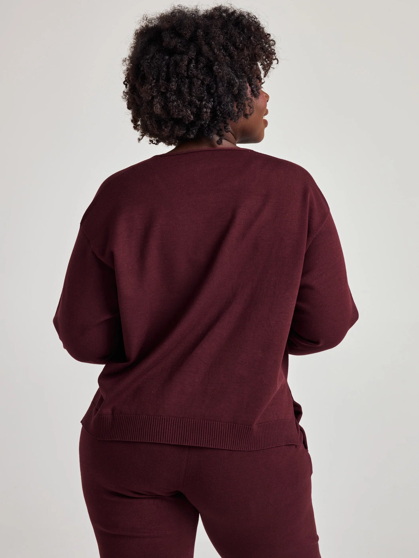 model wears sustainable cozy v neck sweater in burgundy