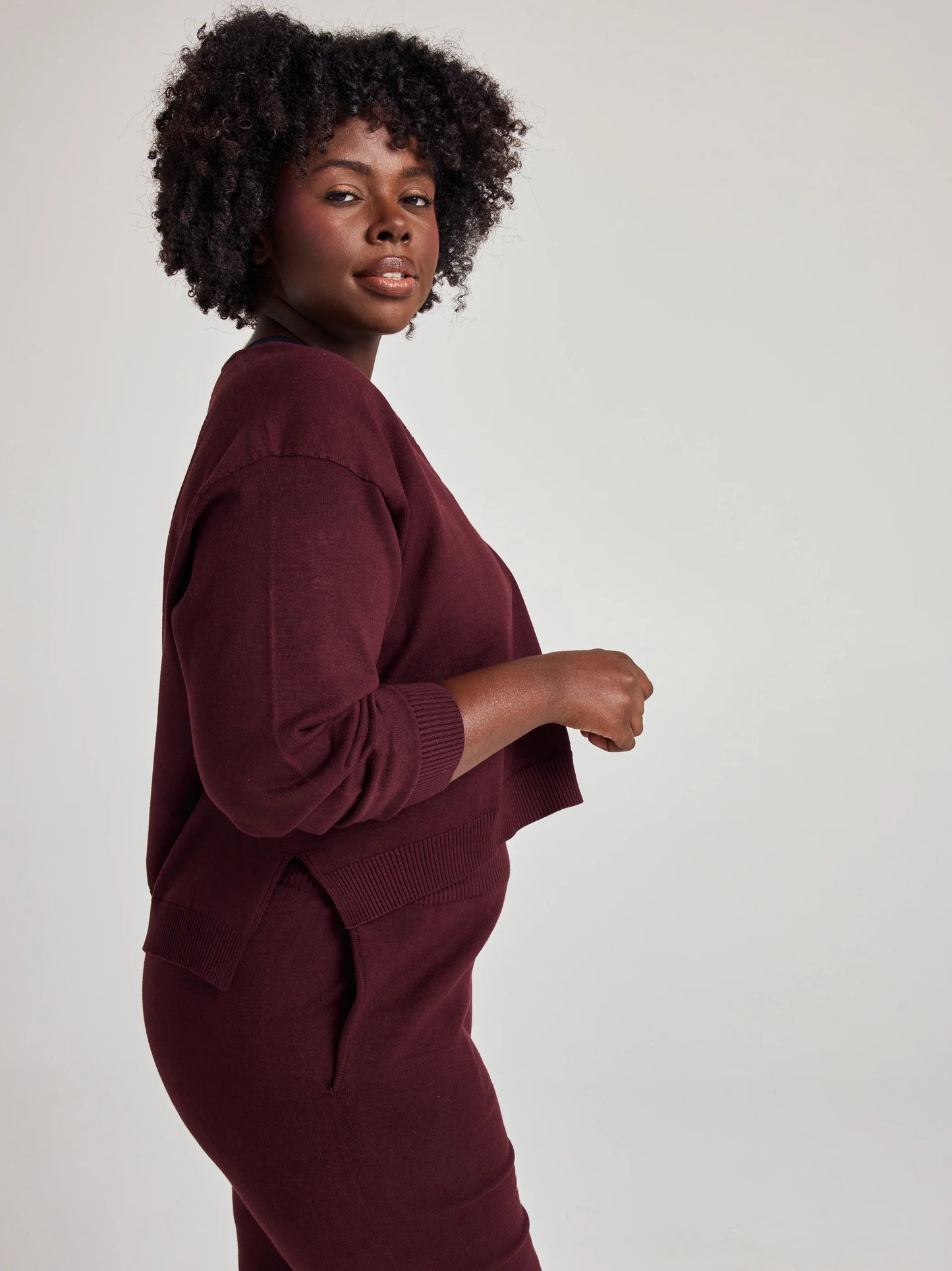 model wears sustainable cozy v neck sweater in burgundy