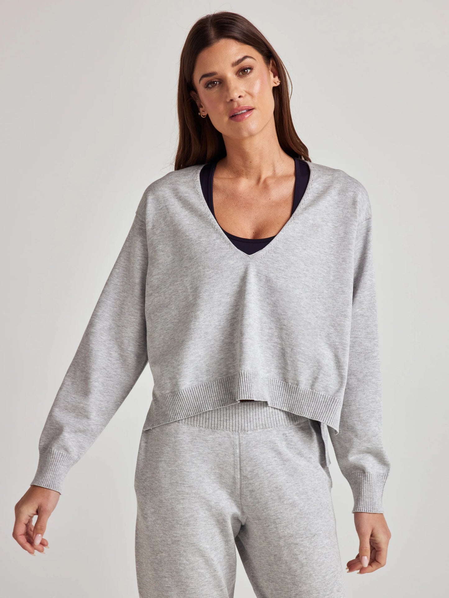 model wears sustainable cozy v neck sweater in grey