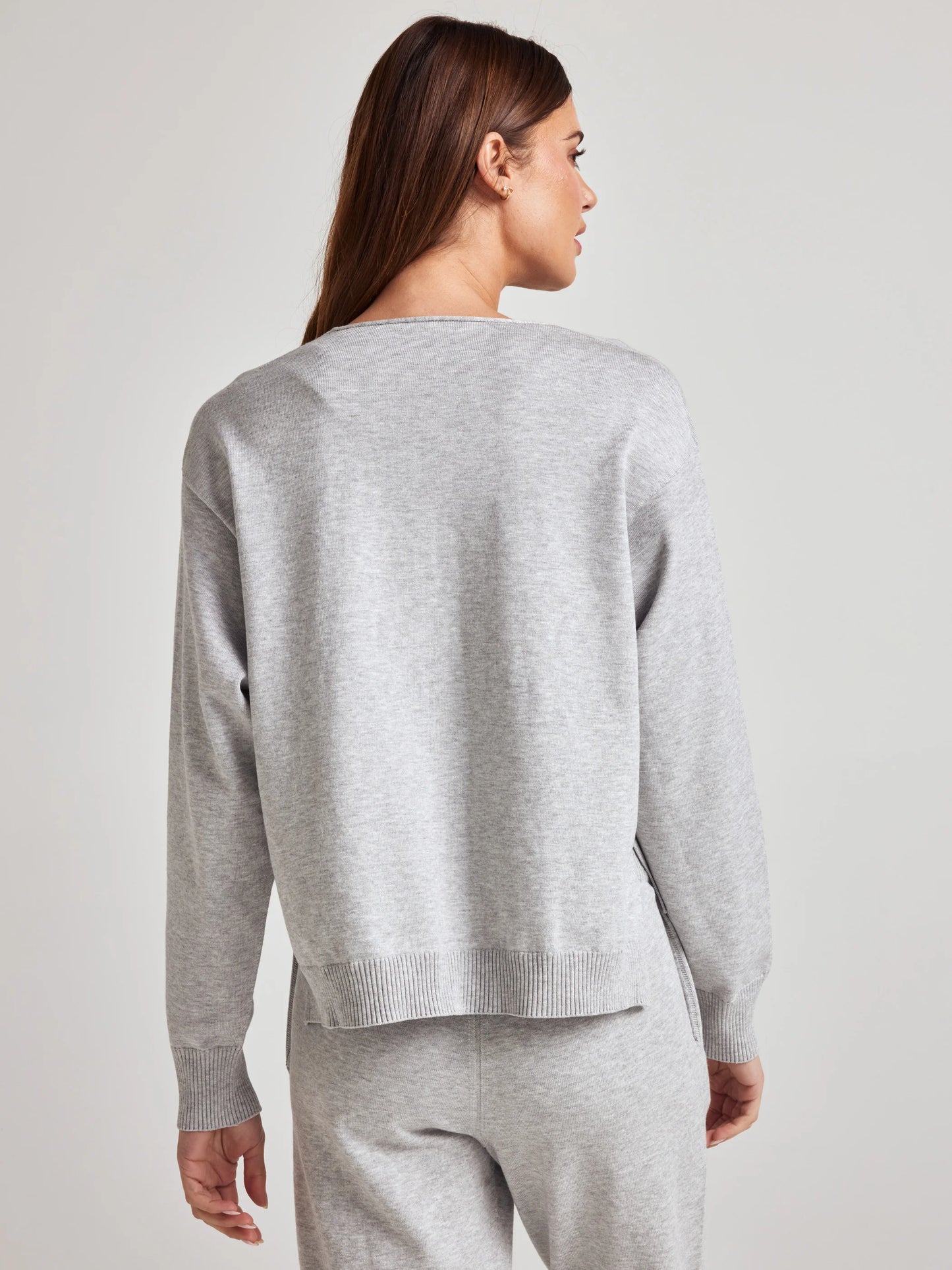 model wears sustainable cozy v neck sweater in grey