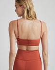 Model poses in burnt orange bralette with corset boning