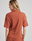model poses in orange thermal button down with seashell buttons