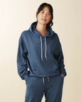 model wears cozy sustainable hoodie with pocket in blue