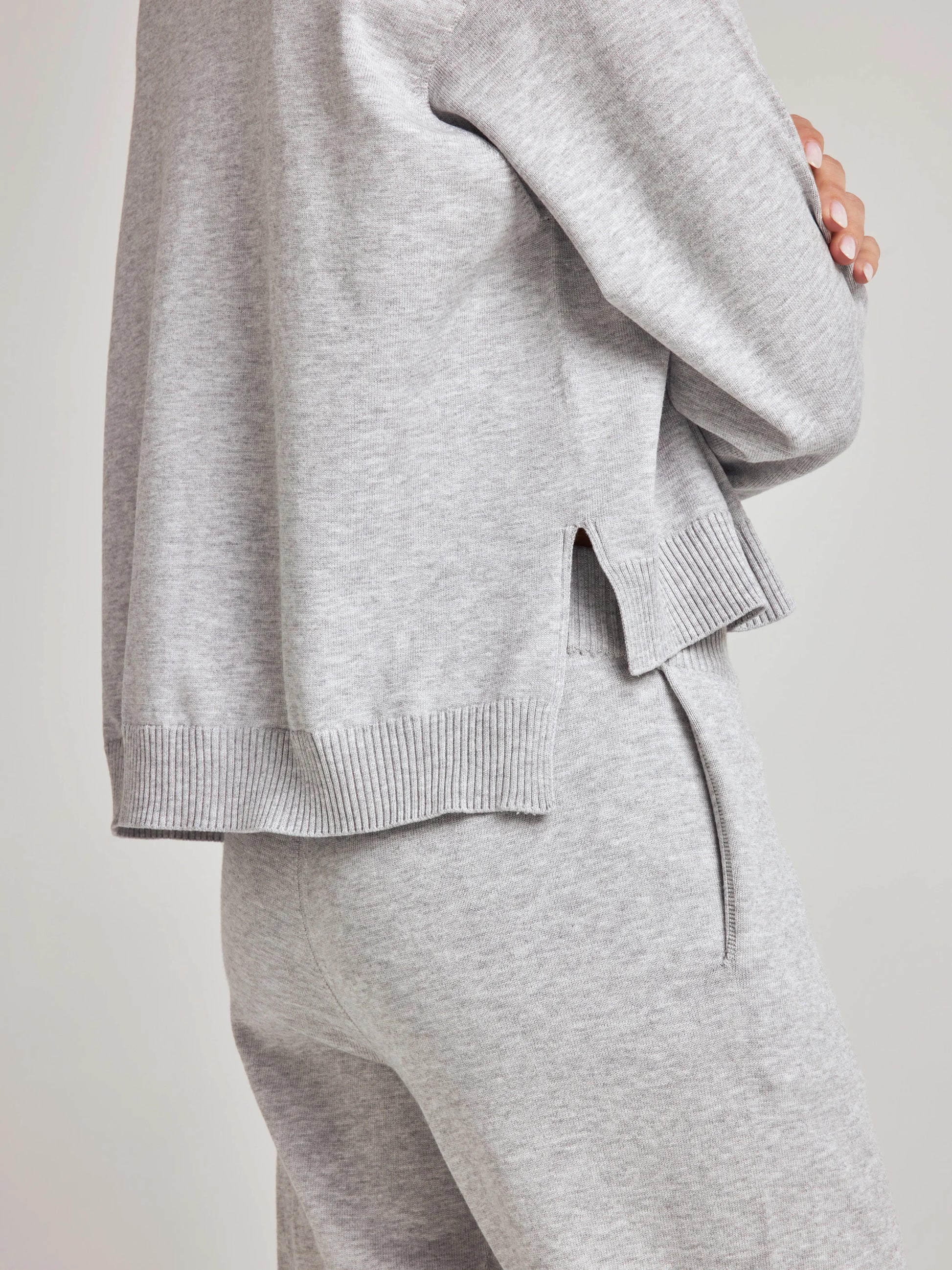 model wears sustainable cozy v neck sweater in grey