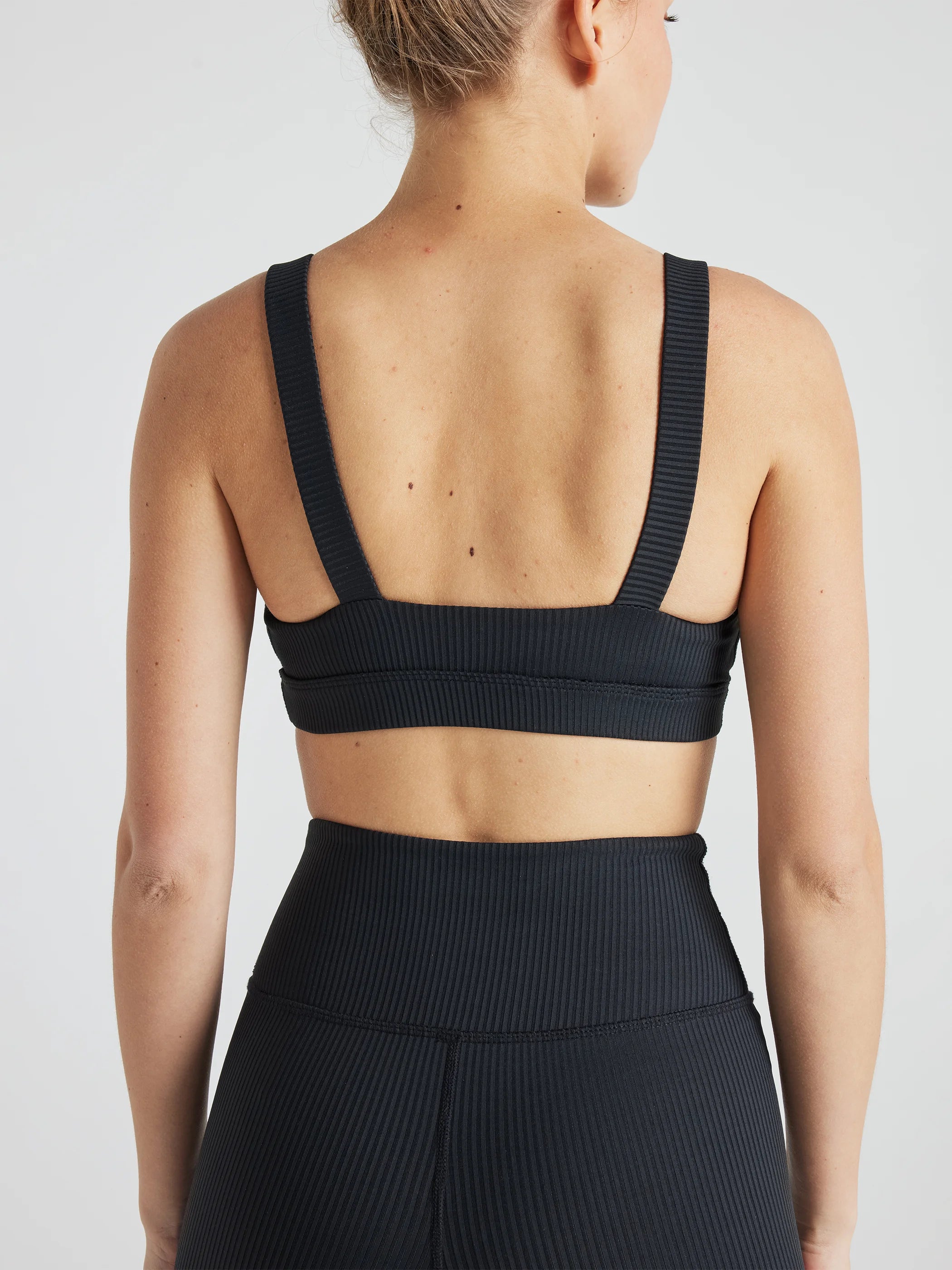 Model wears sustainable square neck black nylon rib sports bra