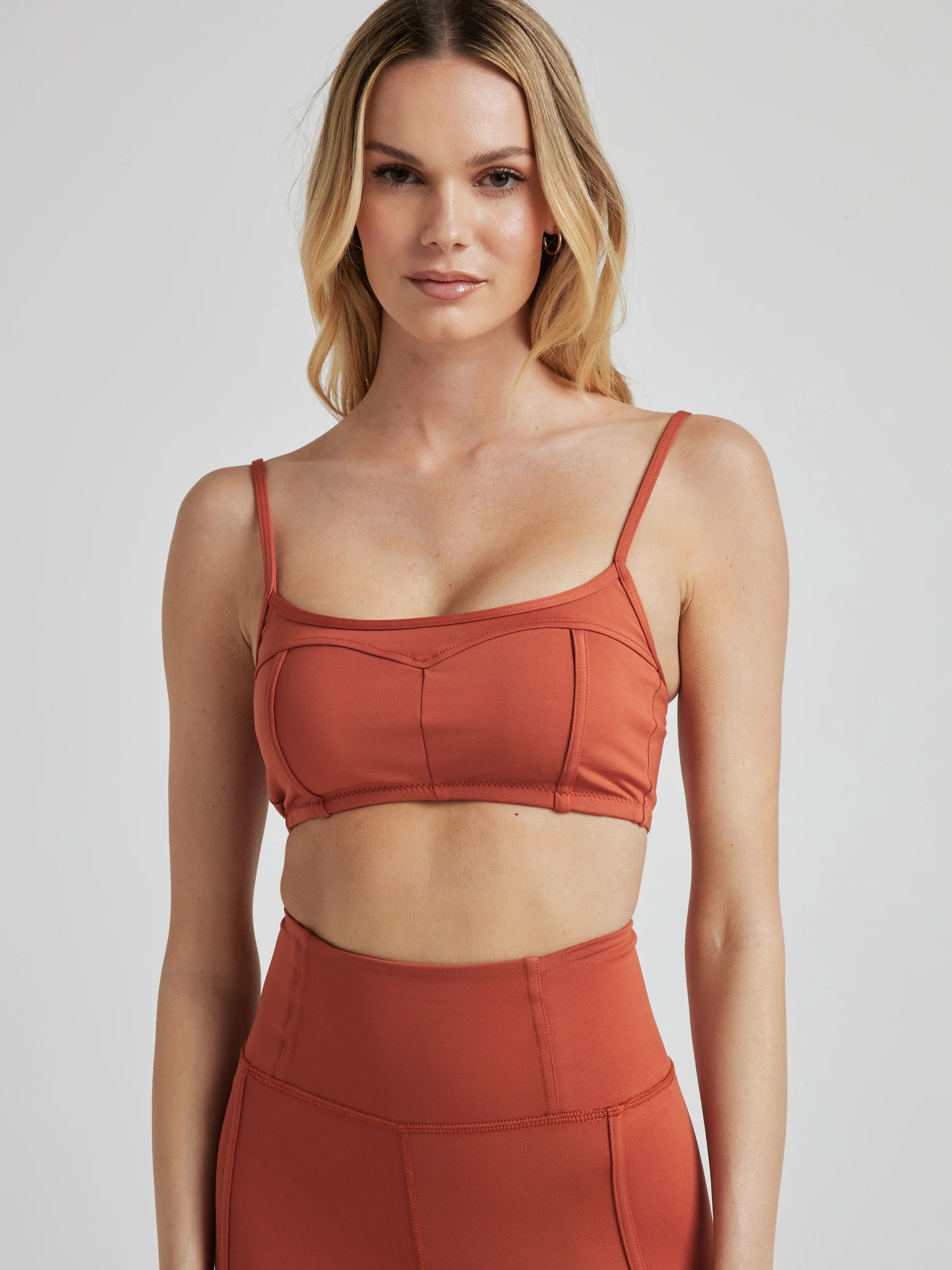 Model poses in burnt orange bralette with corset boning