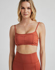 Model poses in burnt orange bralette with corset boning