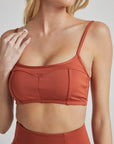 Model poses in burnt orange bralette with corset boning