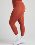 model poses in burnt orange leggings with corset boning