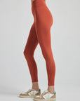 model poses in burnt orange leggings with corset boning