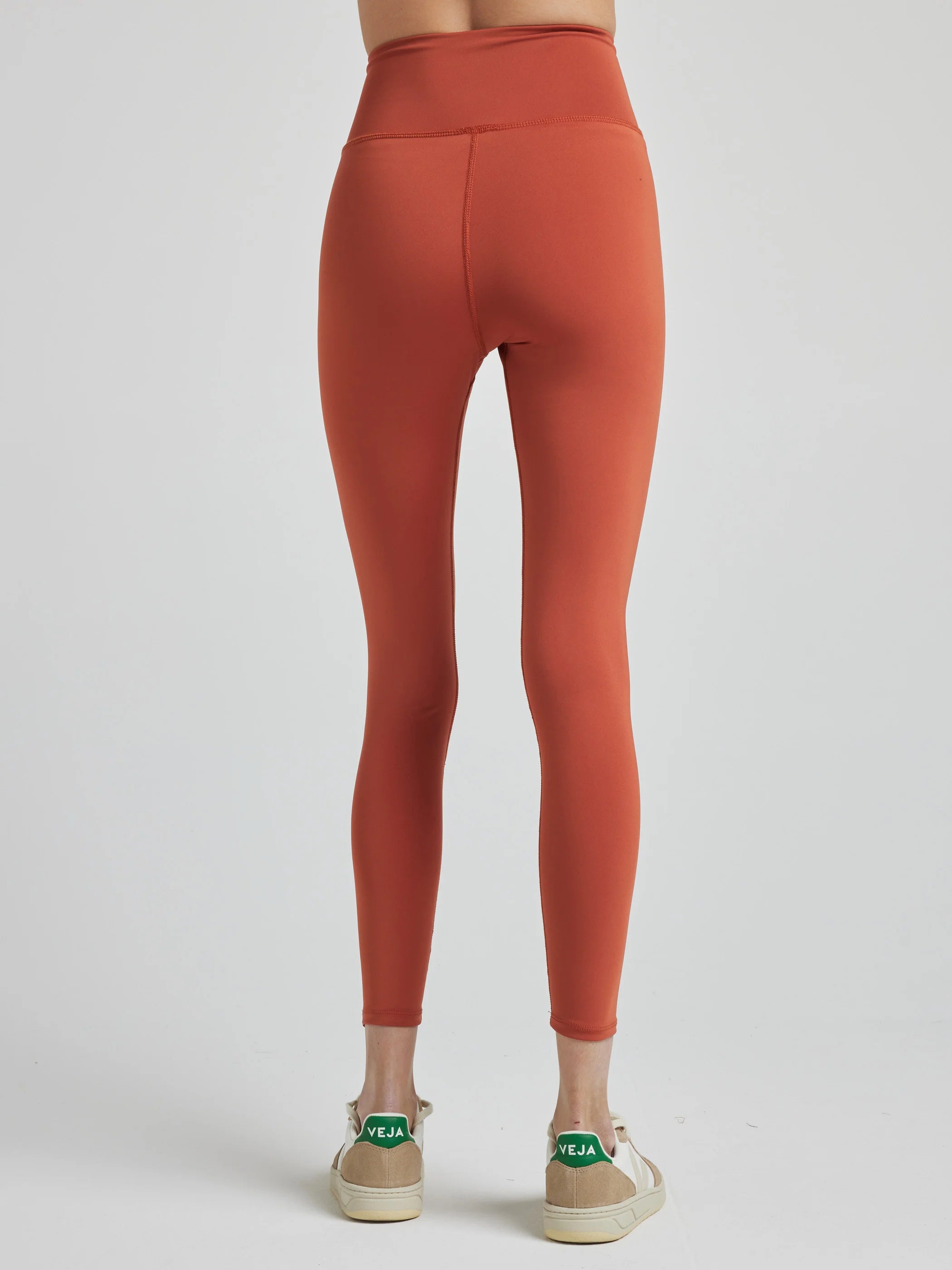 model poses in burnt orange leggings with corset boning