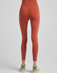 model poses in burnt orange leggings with corset boning