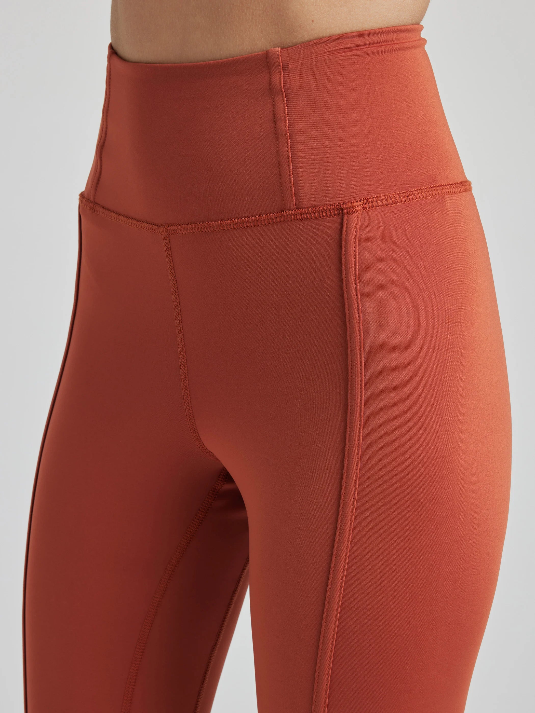 model poses in burnt orange leggings with corset boning