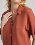 model poses in orange thermal button down with seashell buttons