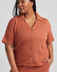 model poses in orange thermal button down with seashell buttons