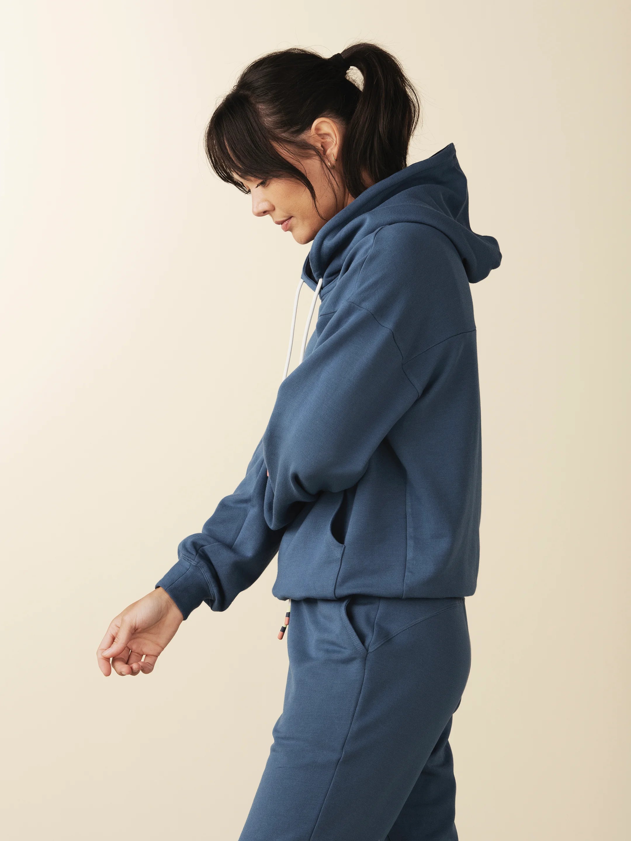 model wears cozy sustainable hoodie with pocket in blue