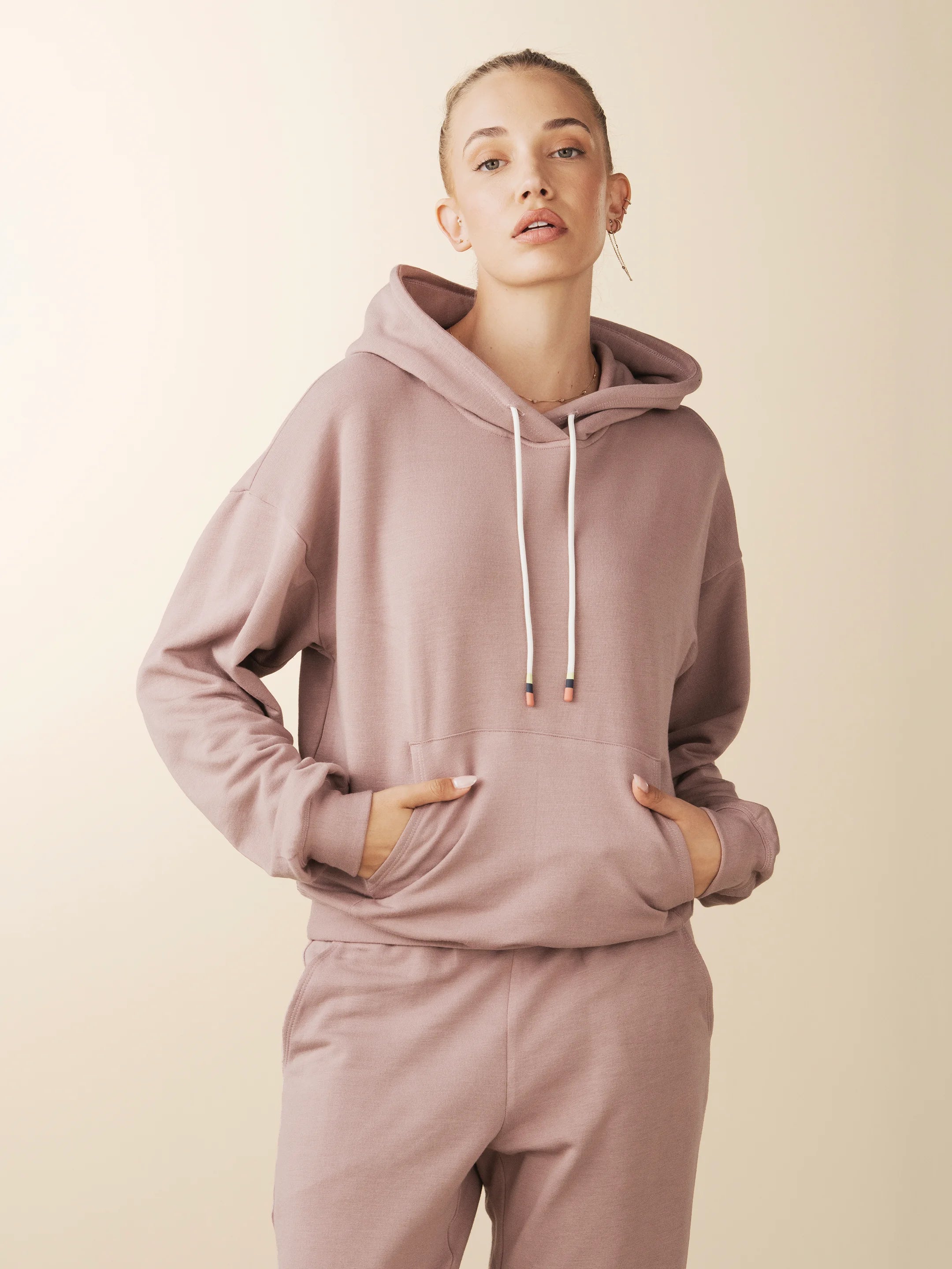 model wears cozy sustainable hoodie with pocket in blush